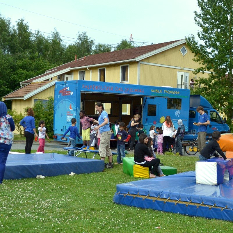 Spielmobil in Flüchtlingsunterkunft mit vielen spielenden Kindern
