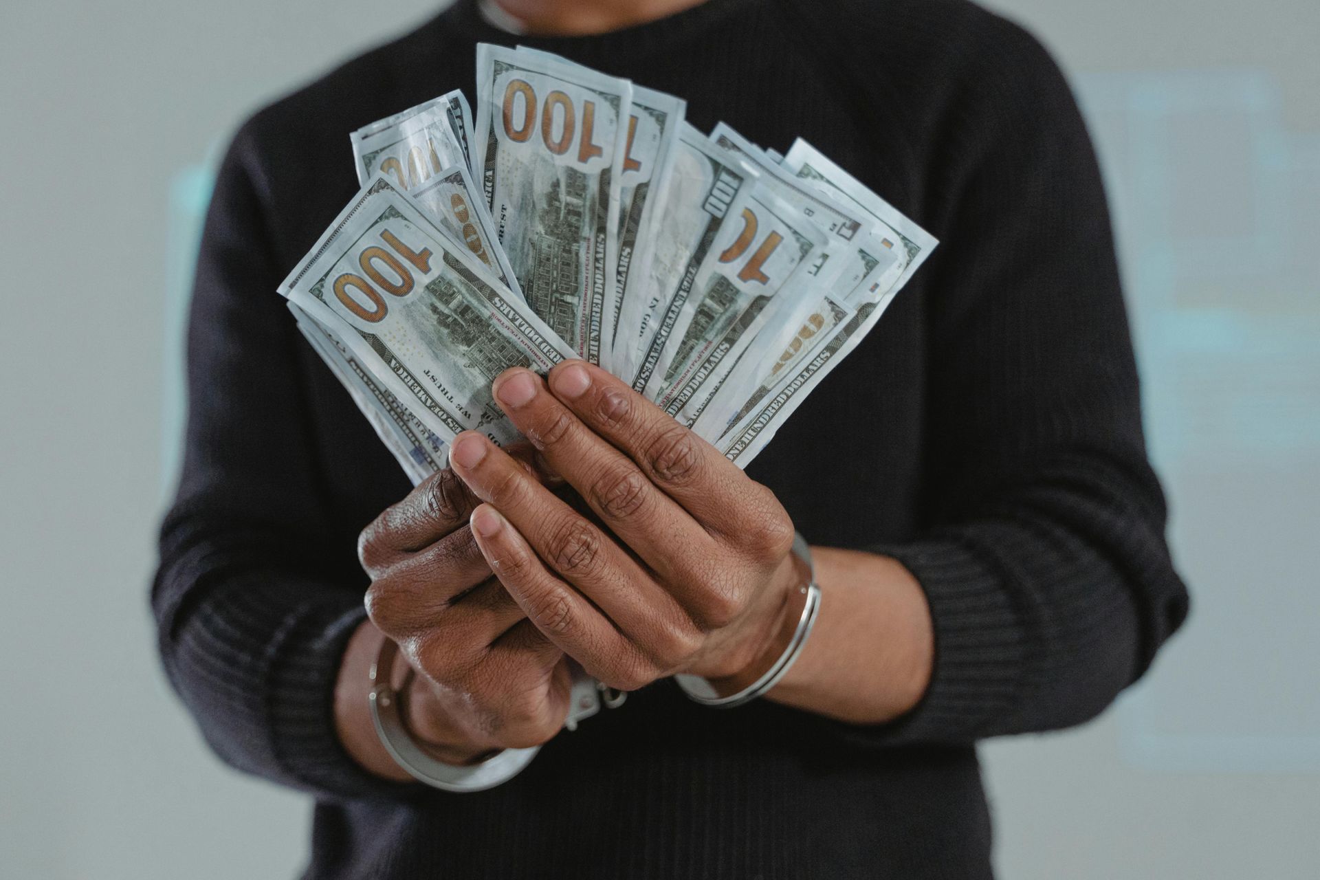 person folding one hundred dollar billls