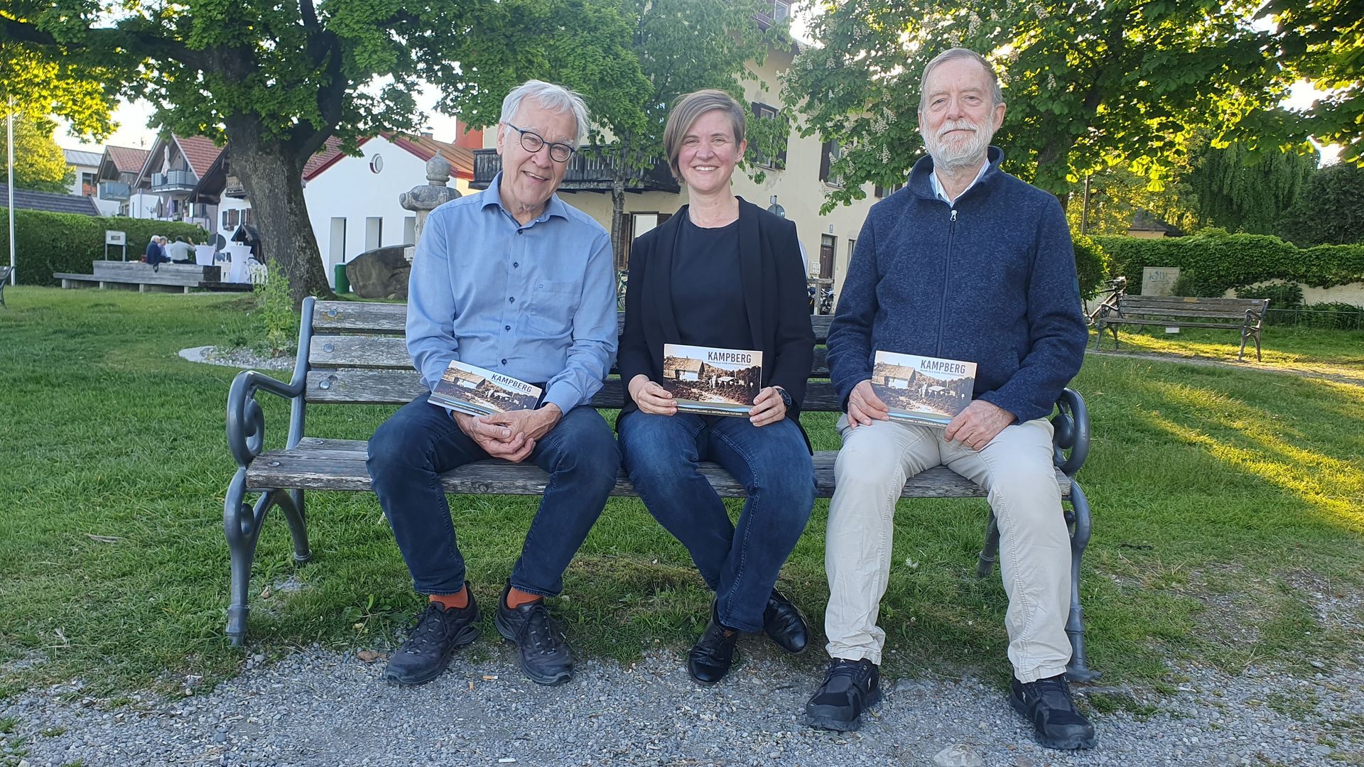 Die drei Kurator*innen der Ausstellung sitzen auf einer Bank