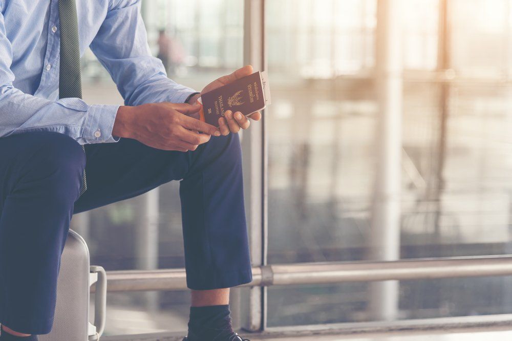 A smart dressed man waiting at an airport with passport in hand