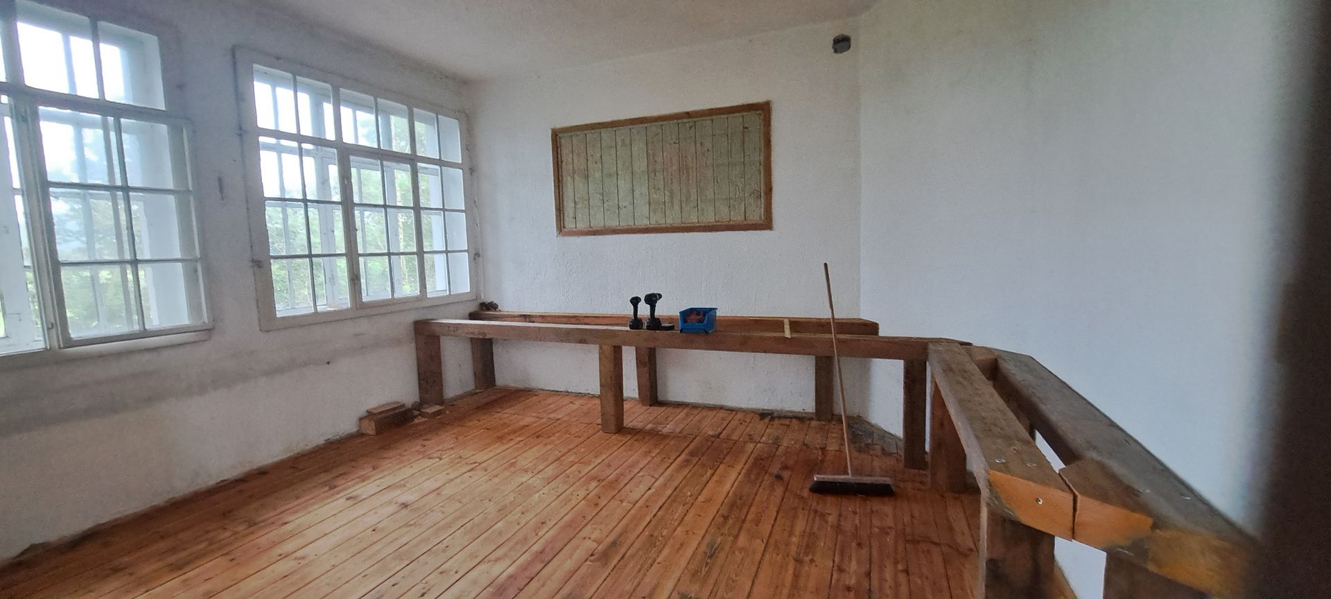 Raum mit Holzfußboden, einem Holzrahmen an der Wand und einer Balkenkonstruktion an der Wand