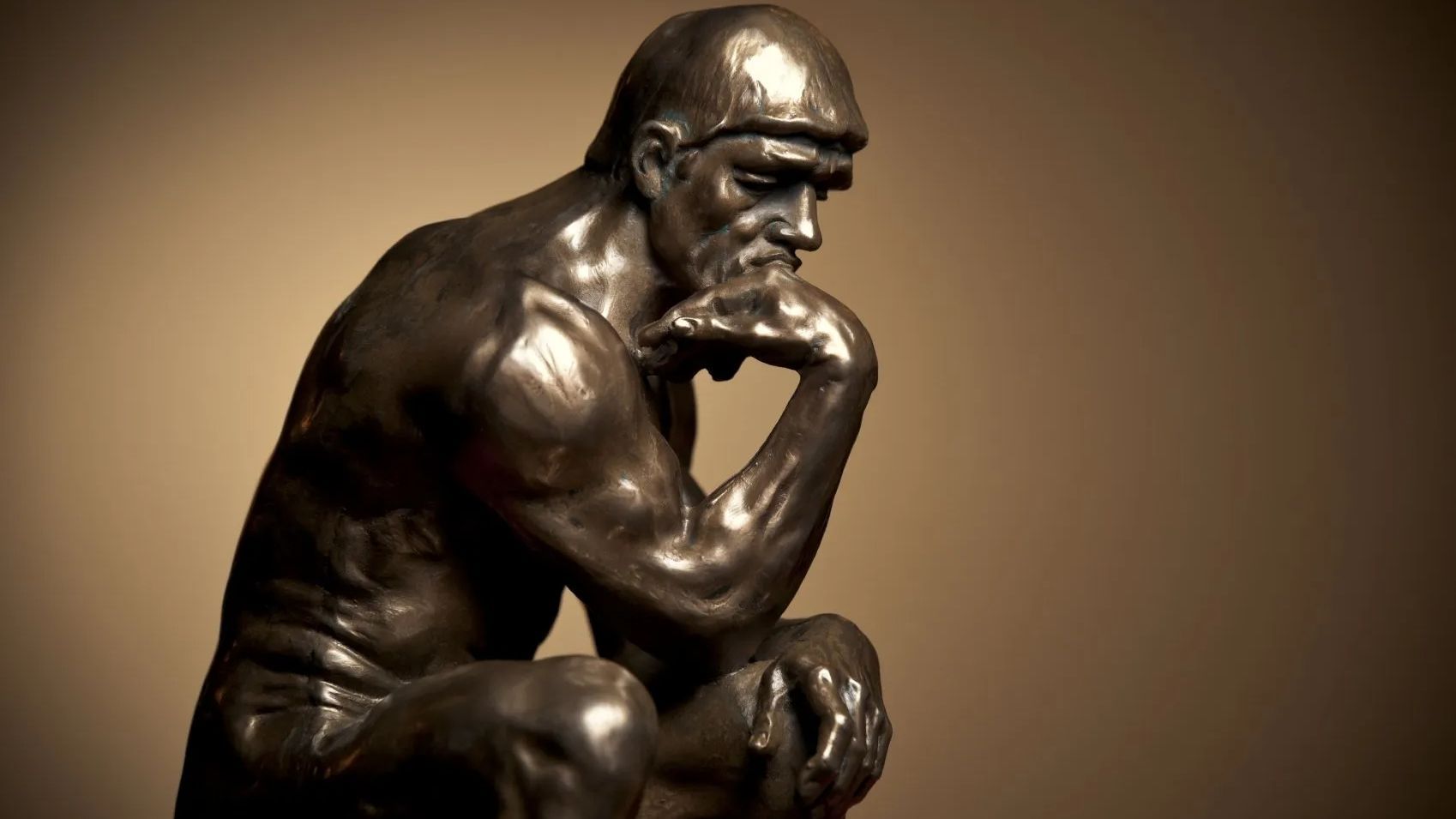 Eine Messingstatue ist einem nachdenklichen Philosophen nachempfunden, der sitzend einen Arm einen Oberschenkel stützt Eine Messingstatue ist einem nachdenklichen Philosophen nachempfunden, der sitzend einen Arm einen Oberschenkel stützt