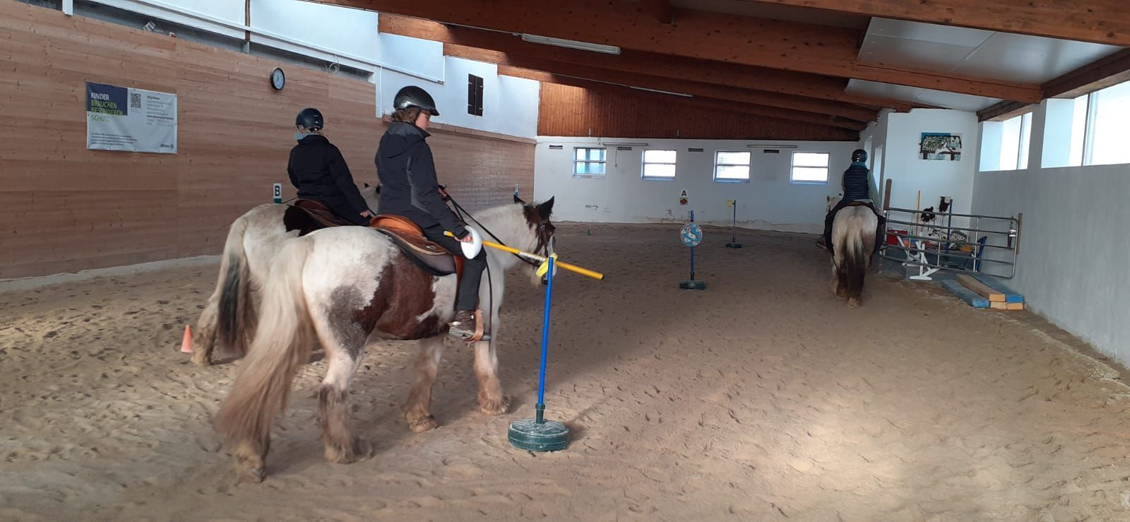 Drei Mädchen nehmen auf Tinkern Reitunterricht in der Reithalle. Drei Mädchen nehmen auf Tinkern Reitunterricht in der Reithalle.