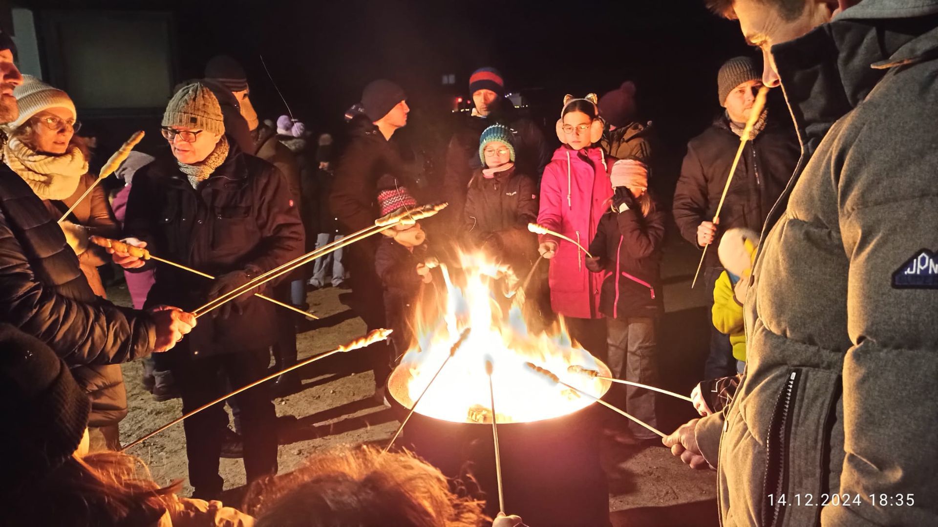 Beim Adventsfenster 2024 in Egersdorf stehen Kinder und Erwachsene um einen großen Feuertopf und machen sich Stockbrot. Beim Adventsfenster 2024 in Egersdorf stehen Kinder und Erwachsene um einen großen Feuertopf und machen sich Stockbrot.