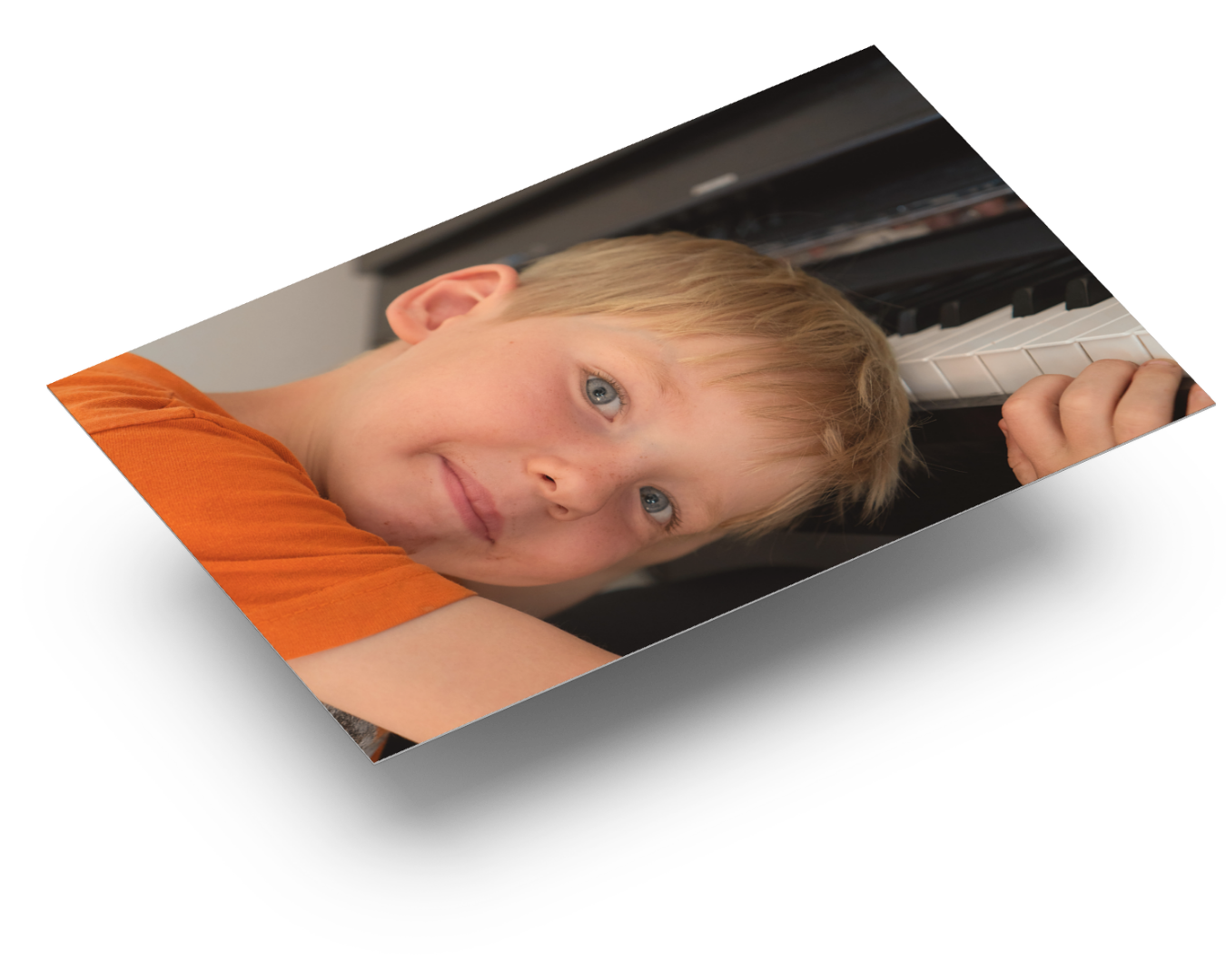 Junge lehnt lächelnd am Klavier