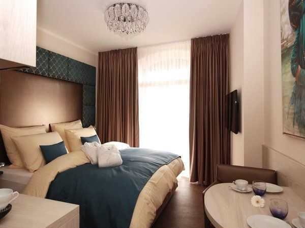 Schlafzimmer im Blue Room mit Boxspringbett, Vorhang und Tageslichtfenster