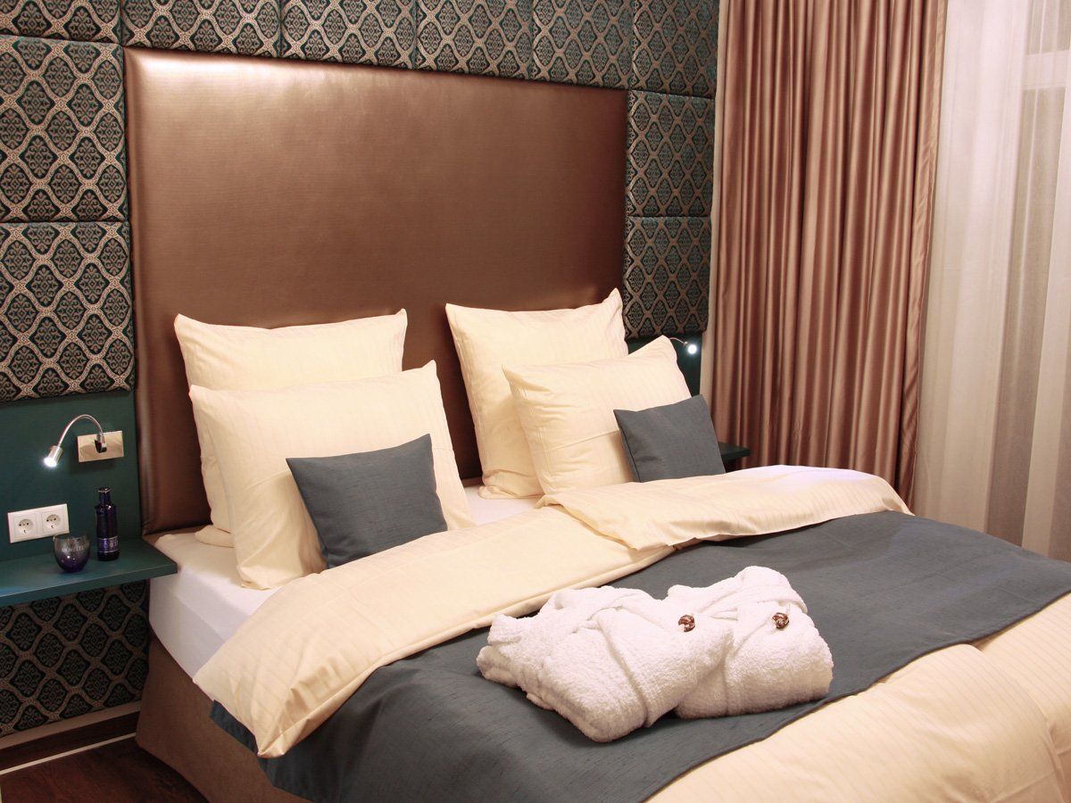 Schlafzimmer im Blue Room mit Boxspringbett, Vorhang und Bademänteln