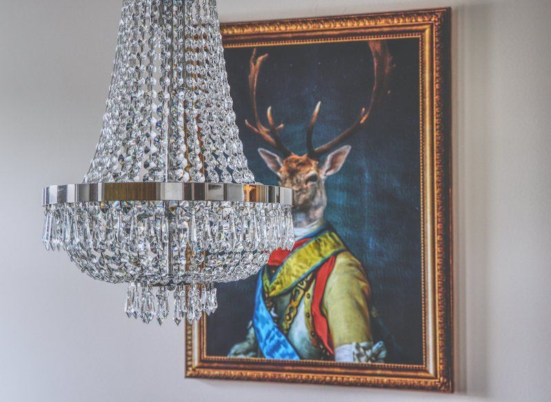 Prunkvoller Kronleuchter vor einem Gemälde mit Hirsch in Uniform – Senator’s Room