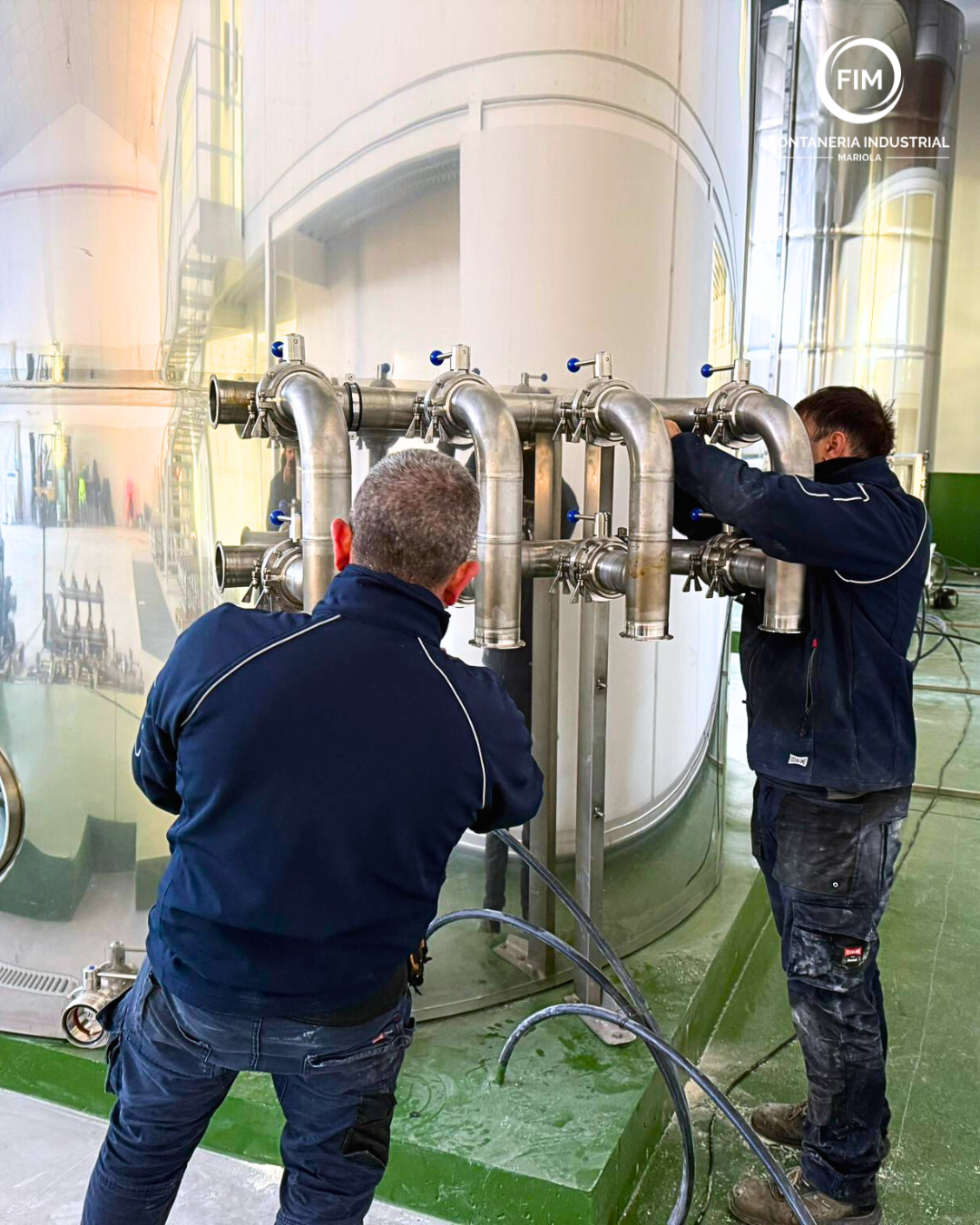 Instalación de tuberías de acero inoxidable en industria alimentaria, con operarios ajustando colect