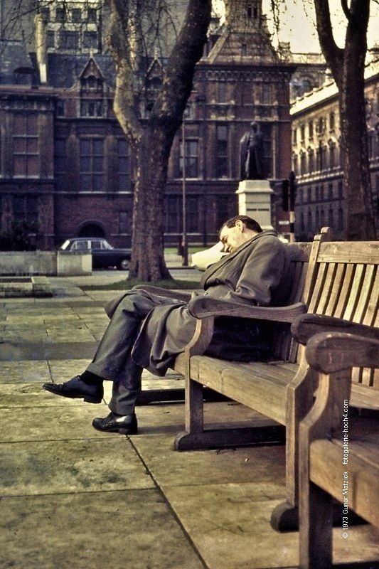 Ein elegant gekleideter Mann sitzt auf einer Parkbank in London. Einen Augenblick ausruhen. Dahinter wacht die Statue mit Georg Canning, der ebenso einen Augeblick Premierminister in England war. Mit nur 119 Tagen Amtszeit hatte er die kürzeste Regierungsverantwortung.