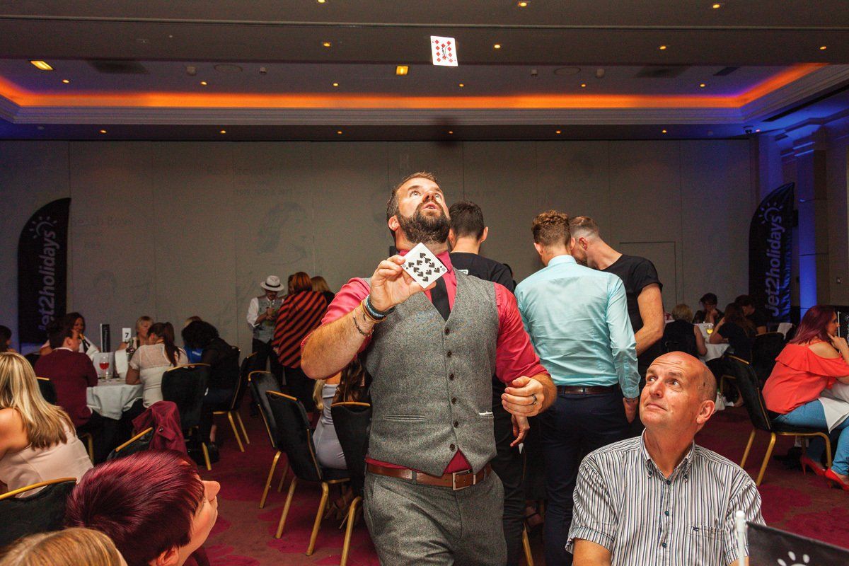 A magician performs a magic trick to event guests.