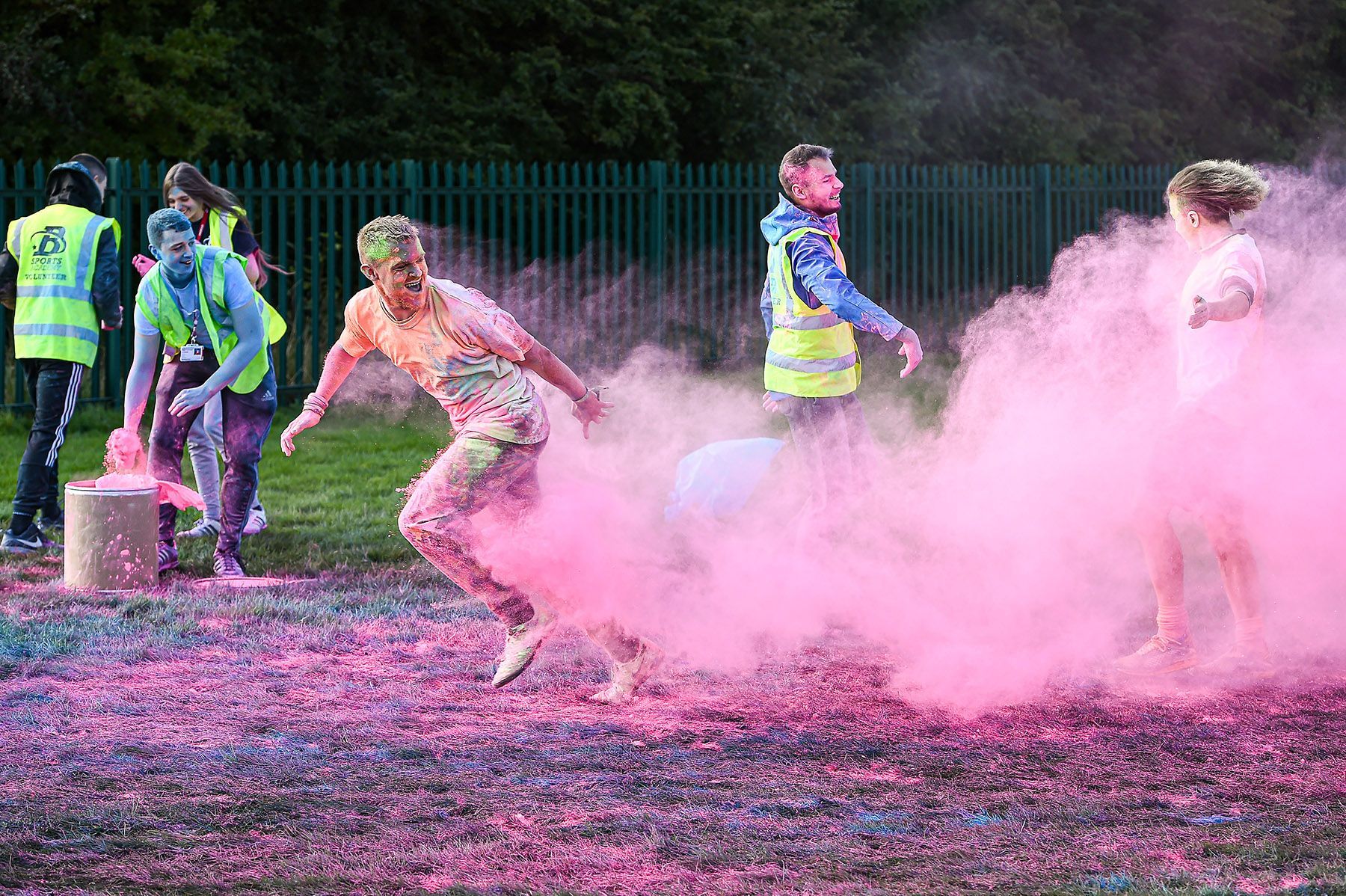 A teenager is covered in pink powder at a colour run event.