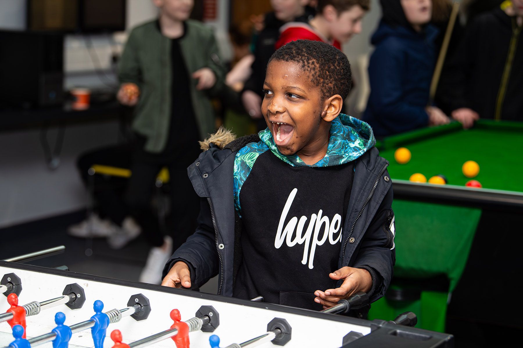 A young boy enjoys himself playing table football.