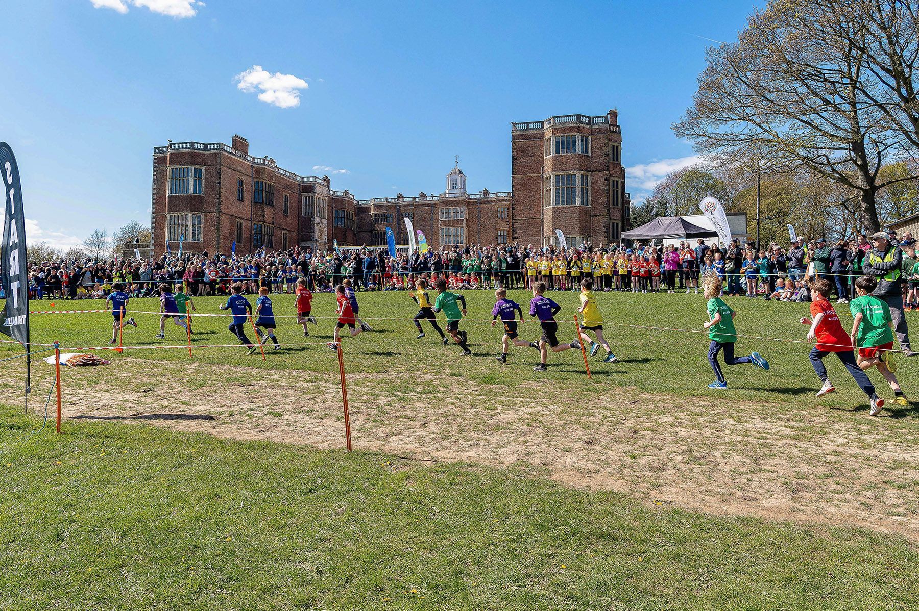 Competitors running towards the finish line at a cross country event.
