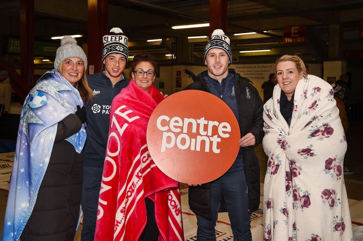 Two Bradford City football players pose with people that are doing a charity Sleep out at Bradford City Football club, on a cold November night.