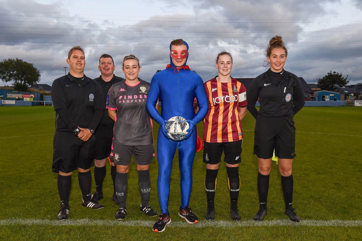 The Be a Hero Mascot lines up with the Captains of Bradford City Ladies and Leeds United Ladies before their football match.