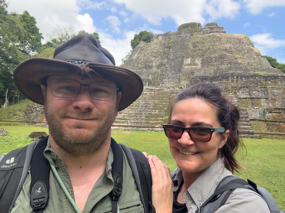 Matthias Brugger und Sandra Brugger machen ein Selfie vor einer alten Maya-Ruine, beide tragen Outdoor-Kleidung und Hüte.