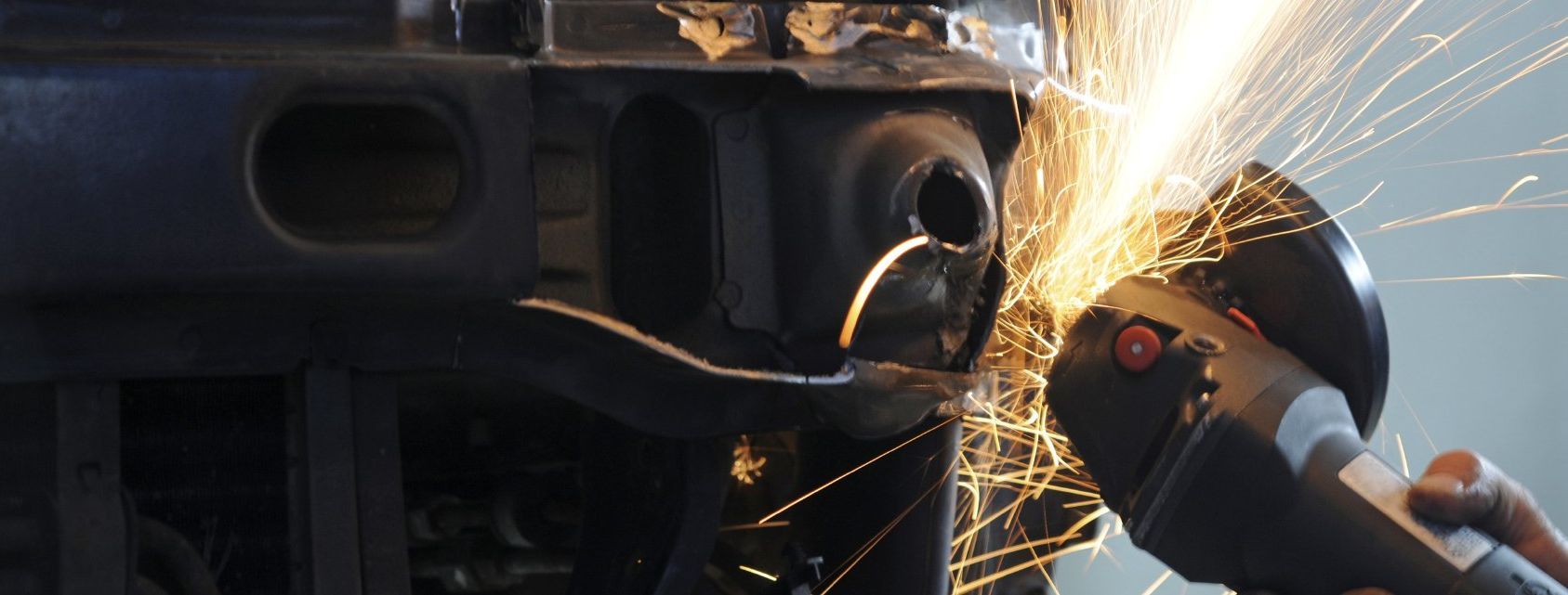 Eine Flex, die ein Stück Blech schneidet. Es ist Funkenflug zu sehen