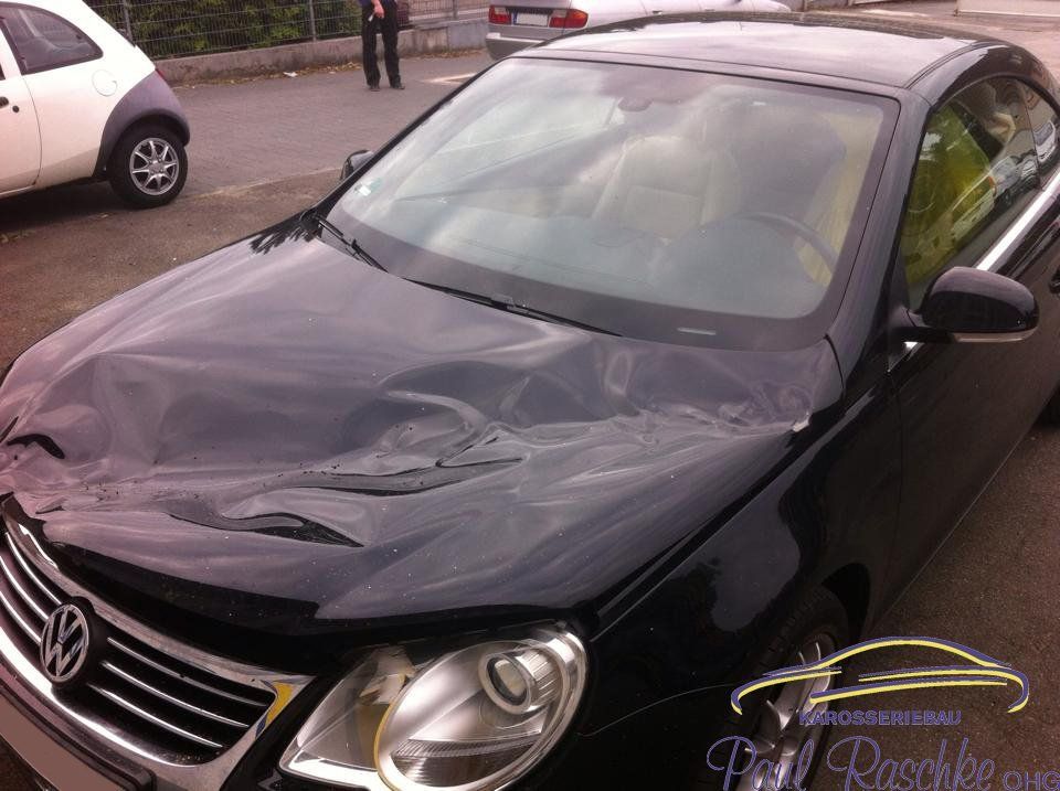 Auf dem Bild ist ein schwarzes Auto zu sehen, welches einen Sturmschaden auf der Haube besitzt.