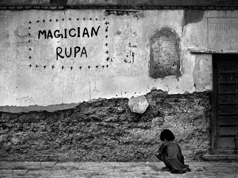 Photographie d'enfant jouant par terre avec son seul imaginaire comme compagnon - photographie noir et blanc de rue