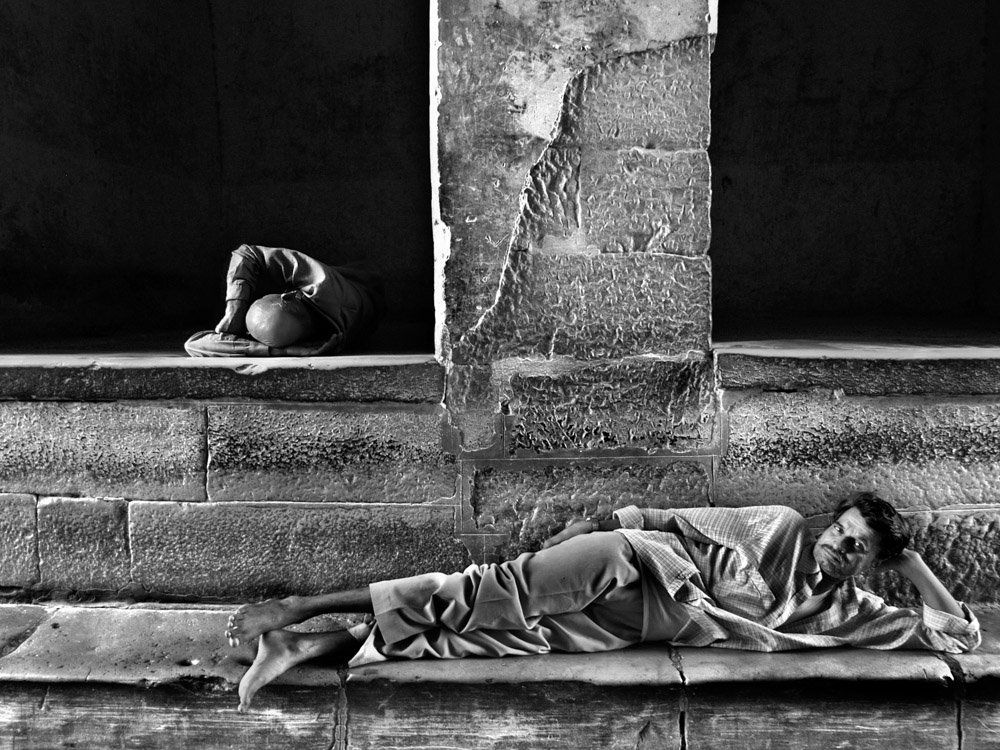 Photographie de personnes somnolant dans la rue dans des encadrements de portes - photo noir et blanc de rue voyage