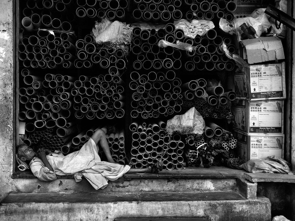 Photographie de personnes somnolant dans la rue dans des encadrements de portes - photo noir et blanc de rue voyage