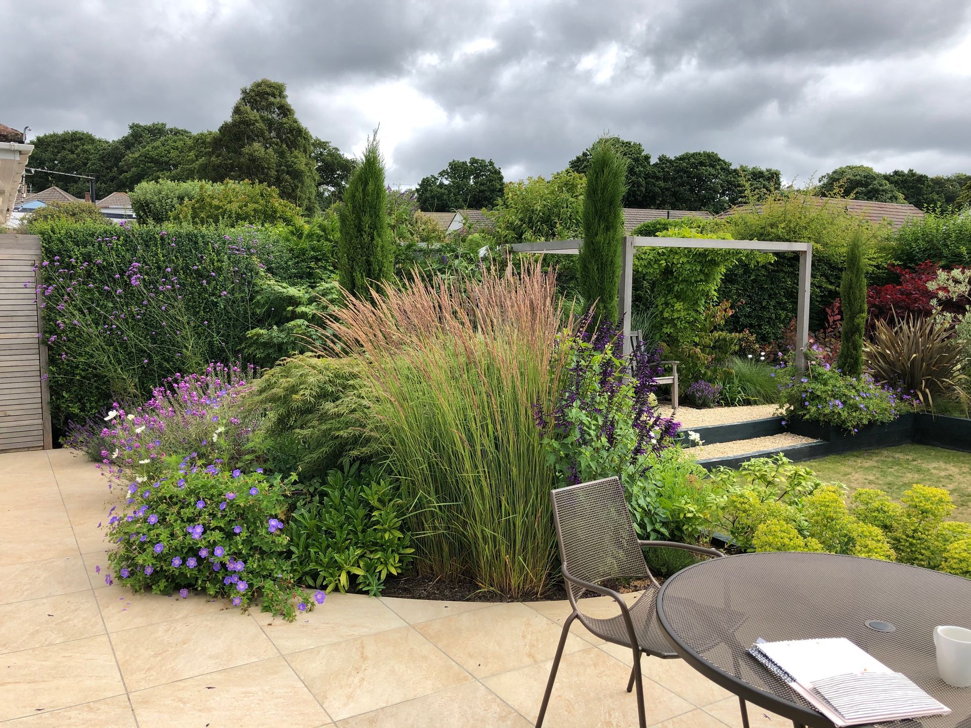 Patio with planted beds and shrubs in Broadstone garden