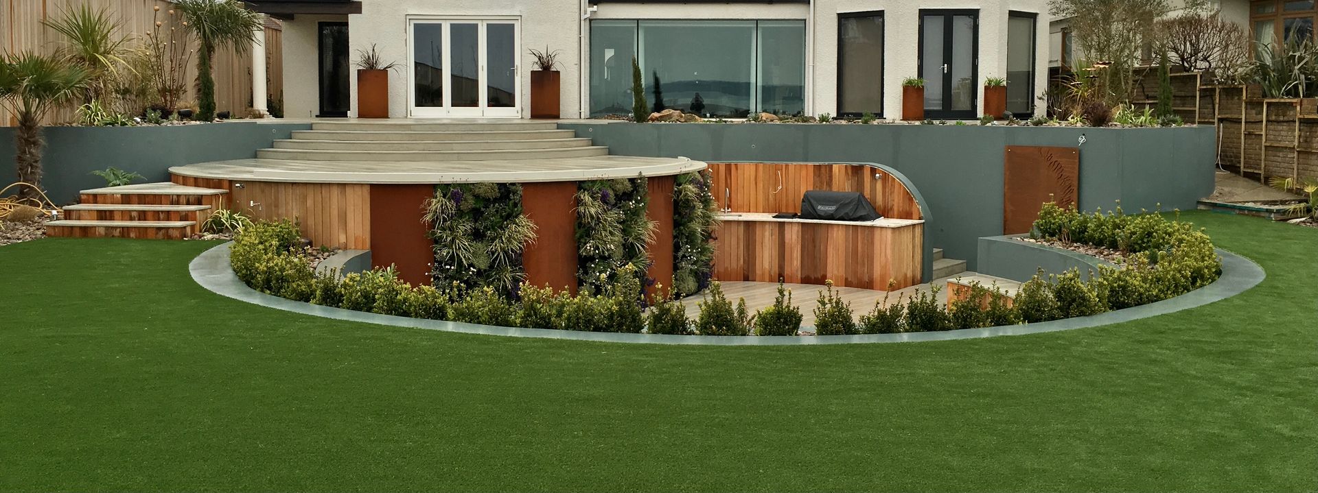 Rounded section of artificial turf surrounding patio in Bournemouth garden