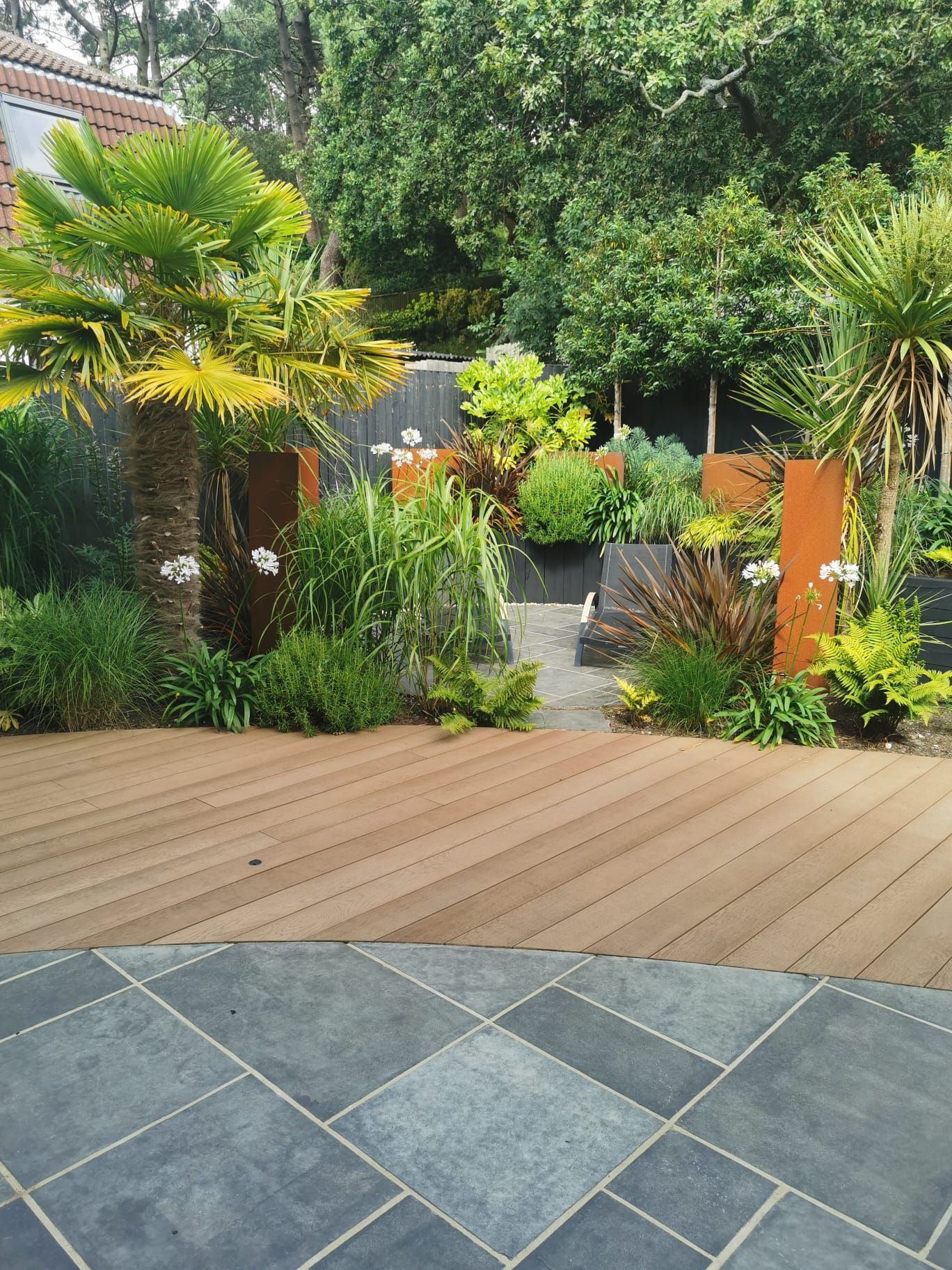 Paved patio with timber deck and planted shrubs in Lilliput garden