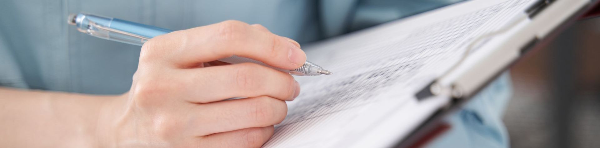 Audits Dienstleistungen Michael Kamp Hand mit Stift schreibt auf Klemmbrett