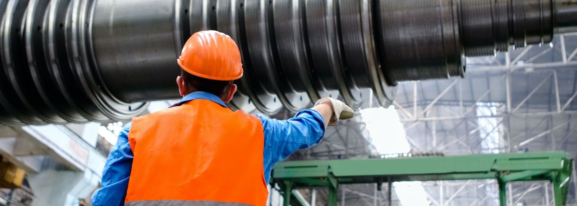 Arbeitsschutz Michael Kamp Mann mit Helm und Warnweste vor großem Industriegerät