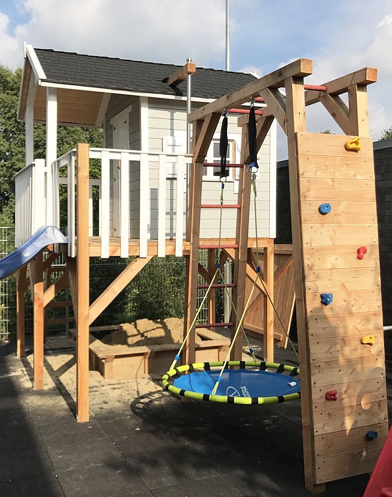 Holzhaus Jansson von Kasohaus aus Hessen mit Nestschaukel, Schaukelanbau und Rutsche. Spielhaus & Stelzenhaus für Ihr Kind