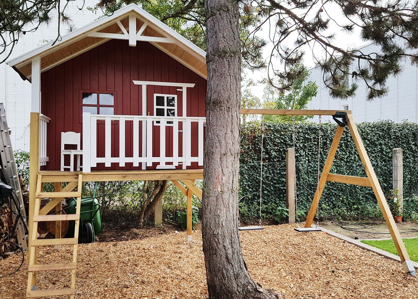 Holzhaus in nordischem Rot - Handgefertigt aus 35325 Mücke, Stelzenhaus, Spielhaus mit Schaukel und Schaukelanbau von kasohaus