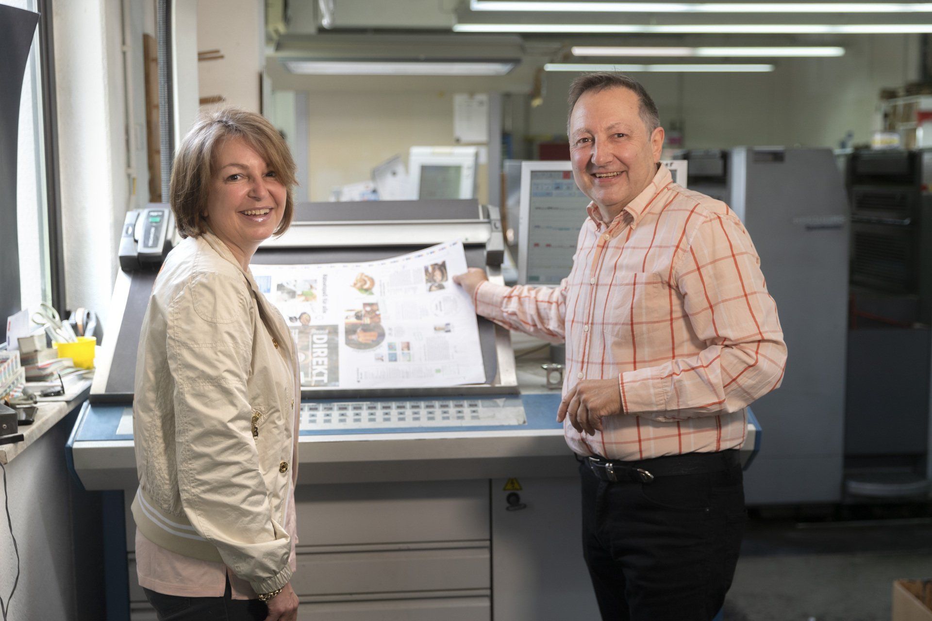 Frau und Herr Thoma stehen an einer unserer Offset Druckmaschinen.