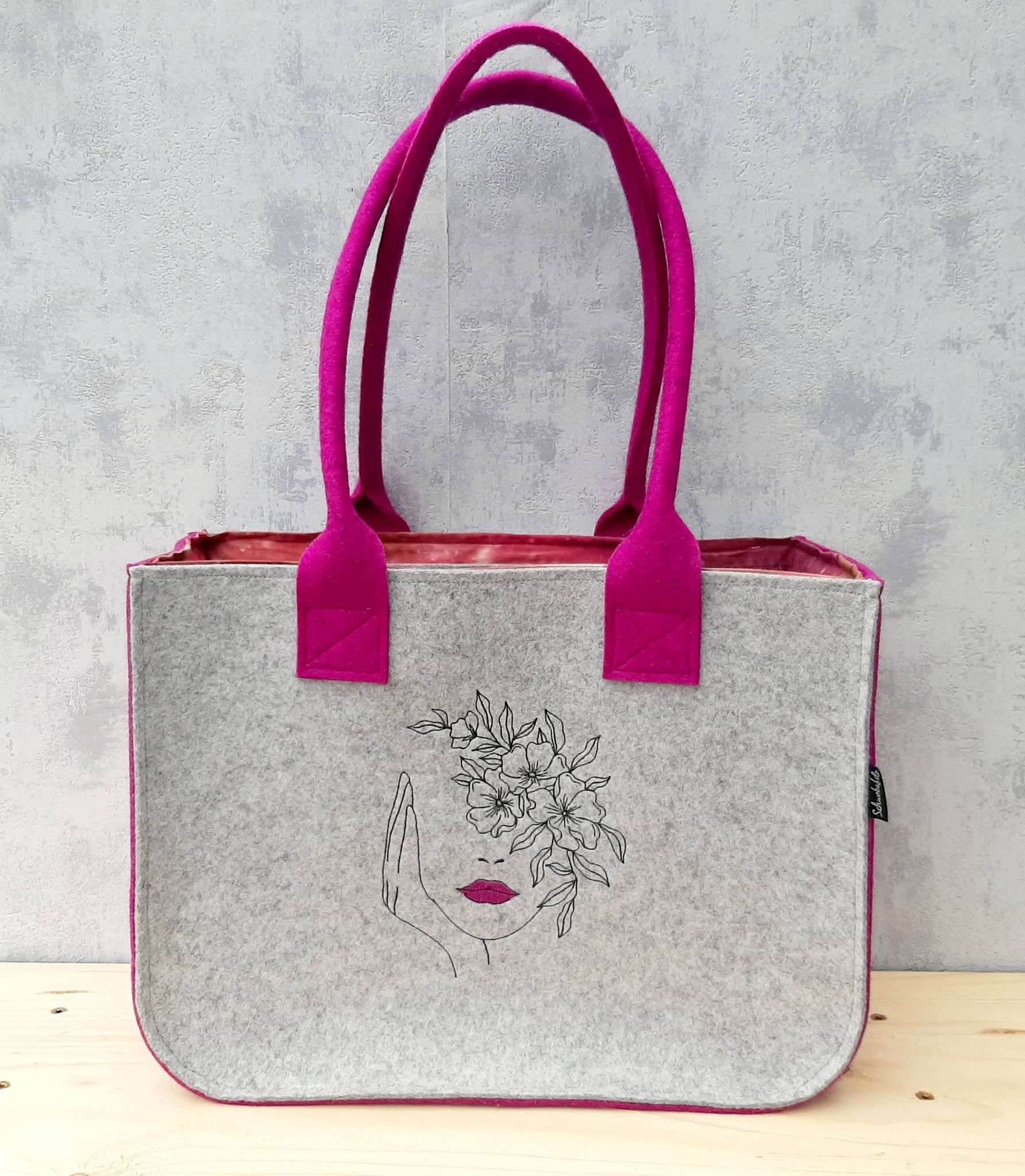 Shopper aus Wollflilz wollweiss / fuchsiamit Innenfutter und Innentasche, bestickt mit Frauengesicht.