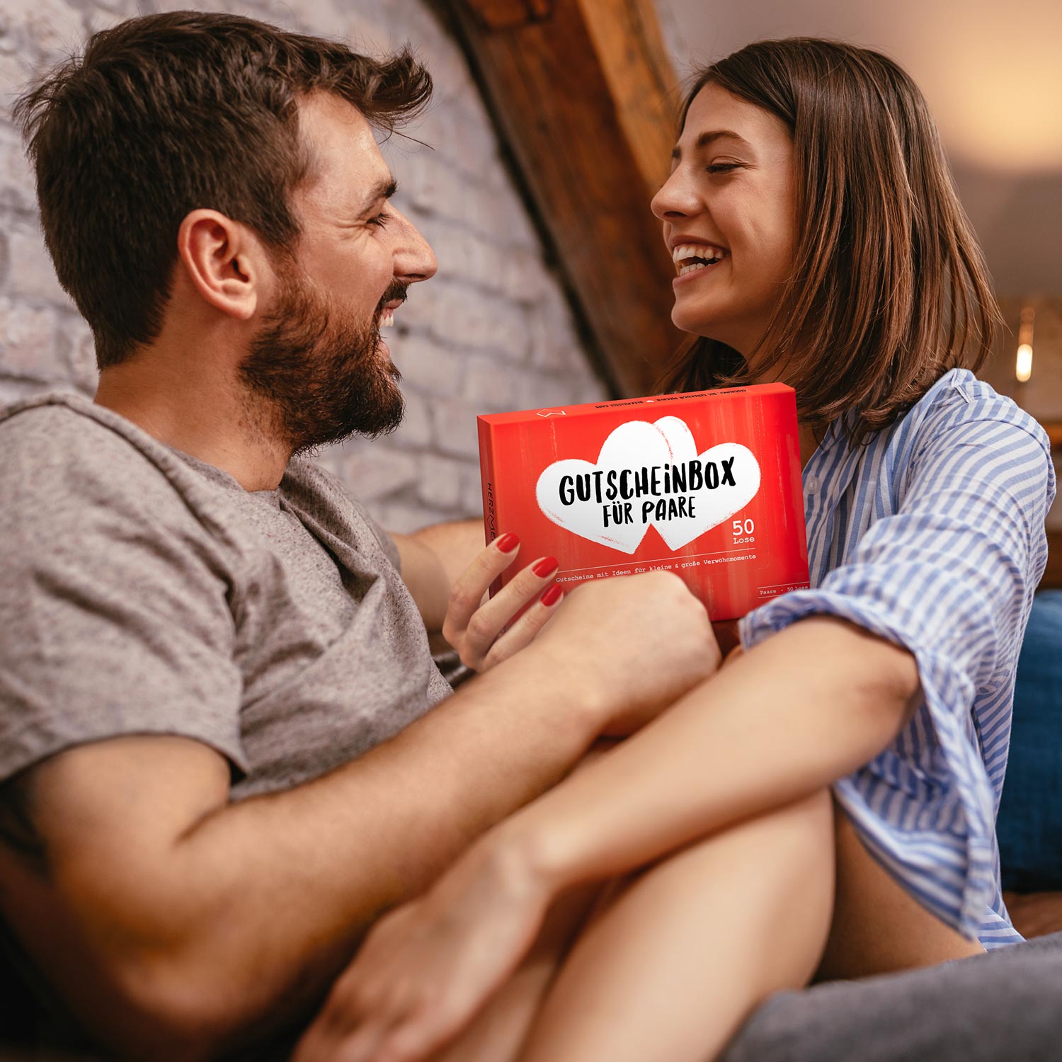 glückliches paar mit gutscheinbox als geschenkidee und geschenk zu hochzeitstag, valentinstag, verlobung, geburtstag von herzmeister