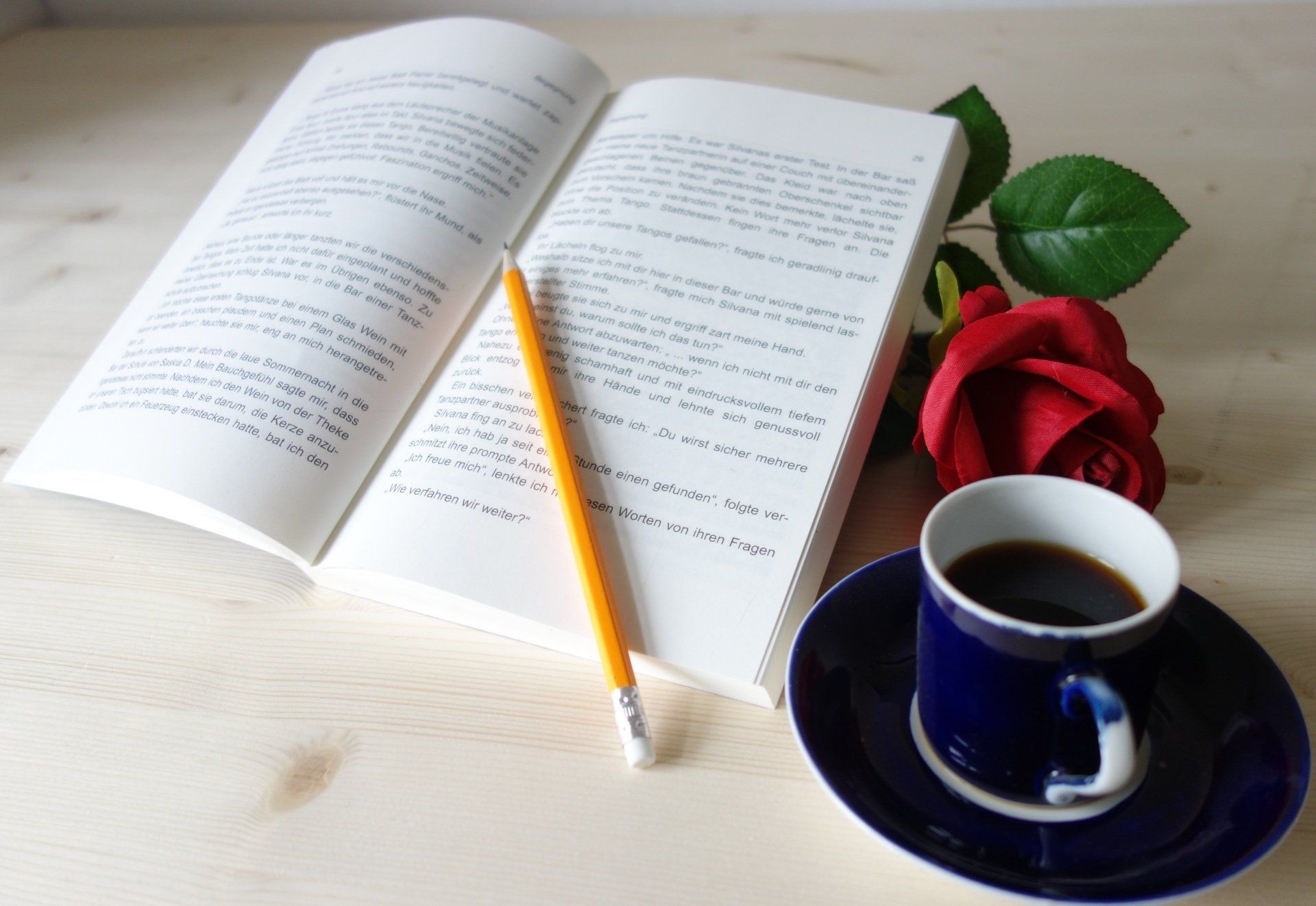 Buch lesen und Kaffee trinkenk Buch Tango mit dem Teufel, Kaffee, rote Rose zum Kaffee