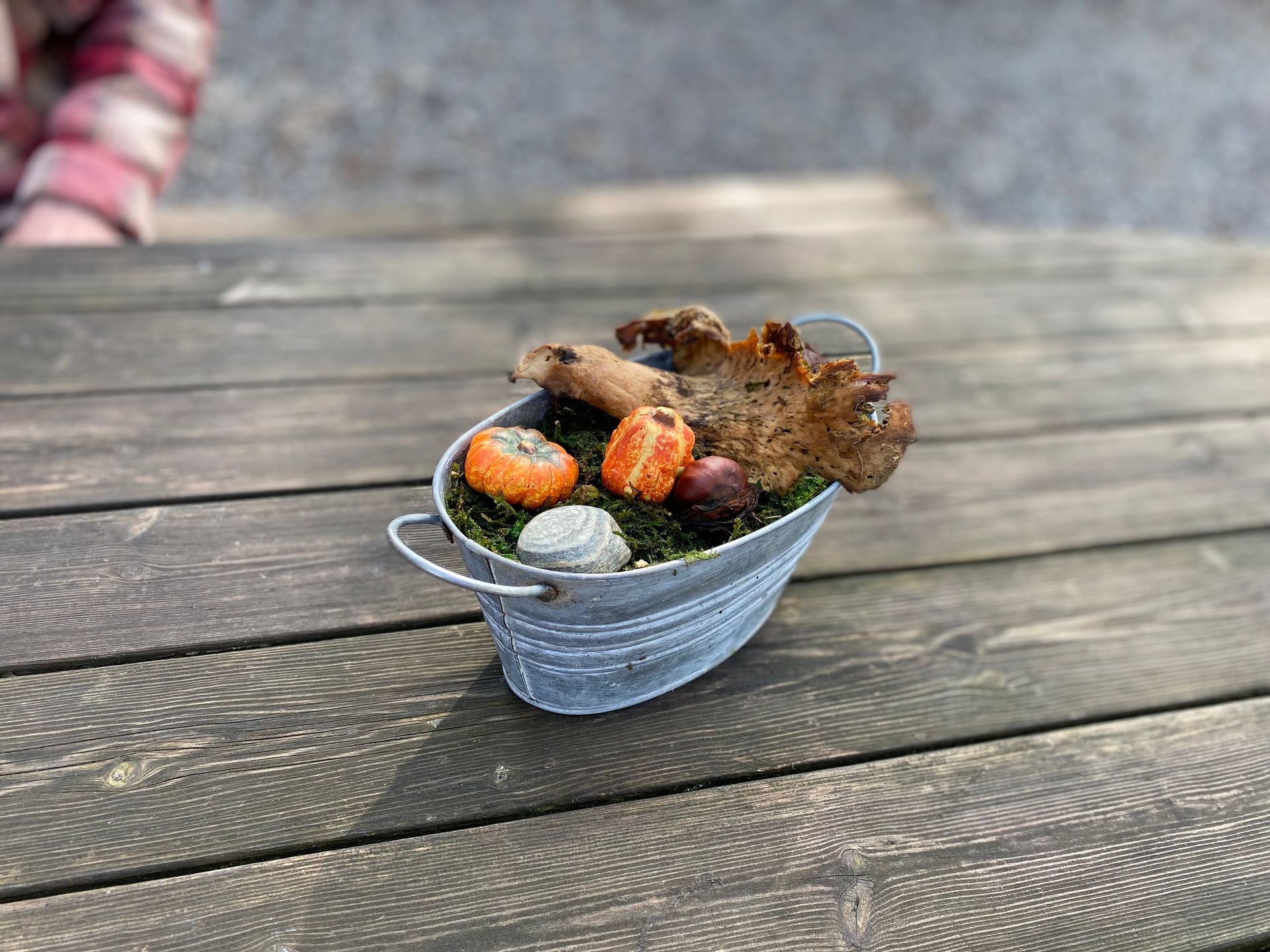 Kleine Zinkschüssel mit Herbstdeko auf einem Holztisch