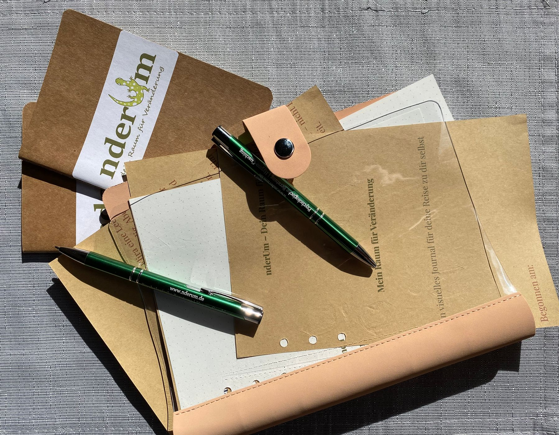 журнал из крафтовой бумаги в розово-прозрачном переплете, записные книжки и ручки с логотипом