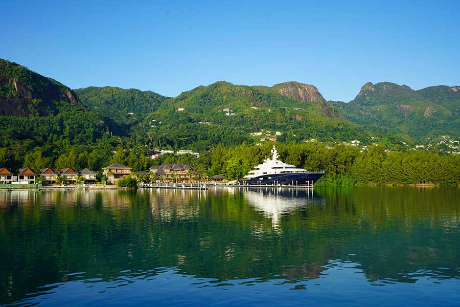 Large luxury yacht docked in a calm bay surrounded by green tropical mountains Large luxury yacht docked in a calm bay surrounded by green tropical mountains