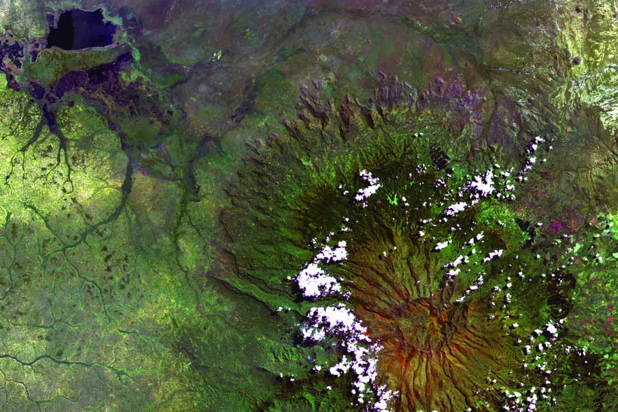 The Bantu-speaking Gishu (Gisu), who grow coffee, bananas, millet, and corn, occupy the western slopes. Elgonyi was the Maasai name for the mountain. The Scottish explorer Joseph Thomson visited the southern slopes of Elgon in 1883. Mount Elgon, an extinct volcano located on the border between Kenya and Uganda. Its crater, about 8 km in diameter, contains several peaks, the highest of which is Wagagai (4 321 m).