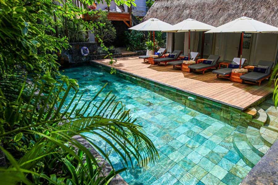 Private resort swimming pool with wooden deck, sun loungers, and tropical plants Private resort swimming pool with wooden deck, sun loungers, and tropical plants
