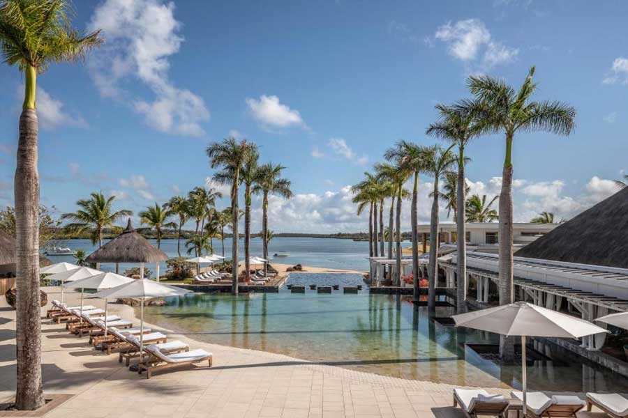 Luxury beach resort infinity pool surrounded by tall palm trees and sunbeds Luxury beach resort infinity pool surrounded by tall palm trees and sunbeds