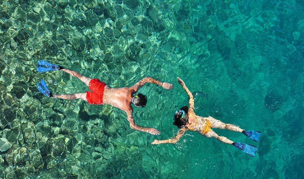 Couple snorkelling together in crystal-clear tropical waters.