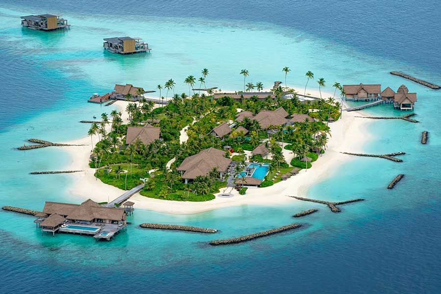 Aerial view of a small Maldives resort island with overwater bungalows and private pools Aerial view of a small Maldives resort island with overwater bungalows and private pools