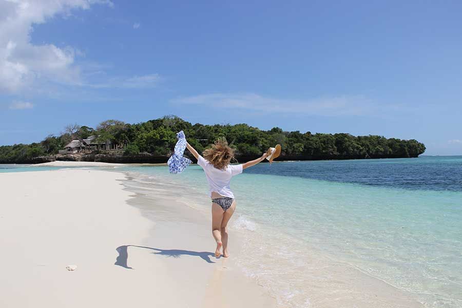 Woman enjoying a peaceful walk along a pristine Zanzibar beach. Woman enjoying a peaceful walk along a pristine Zanzibar beach.