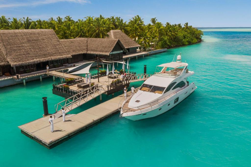 Luxury yacht docked at a tropical island resort pier in clear turquoise water