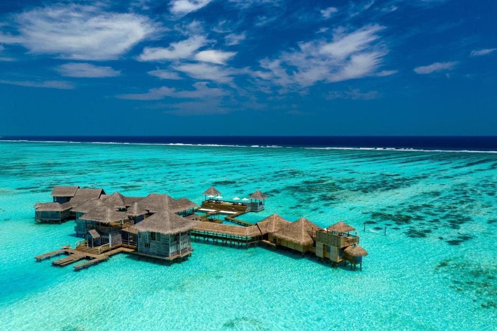 Aerial view of overwater luxury villas connected by wooden boardwalks in a turquoise lagoon Aerial view of overwater luxury villas connected by wooden boardwalks in a turquoise lagoon