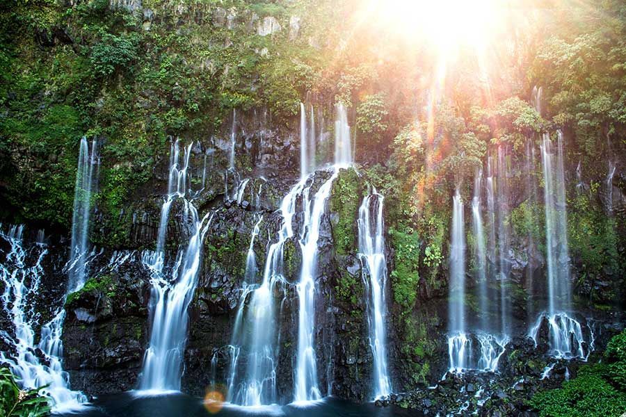 Multiple cascading waterfalls flowing down a green, rocky cliff in Réunion Island Multiple cascading waterfalls flowing down a green, rocky cliff in Réunion Island