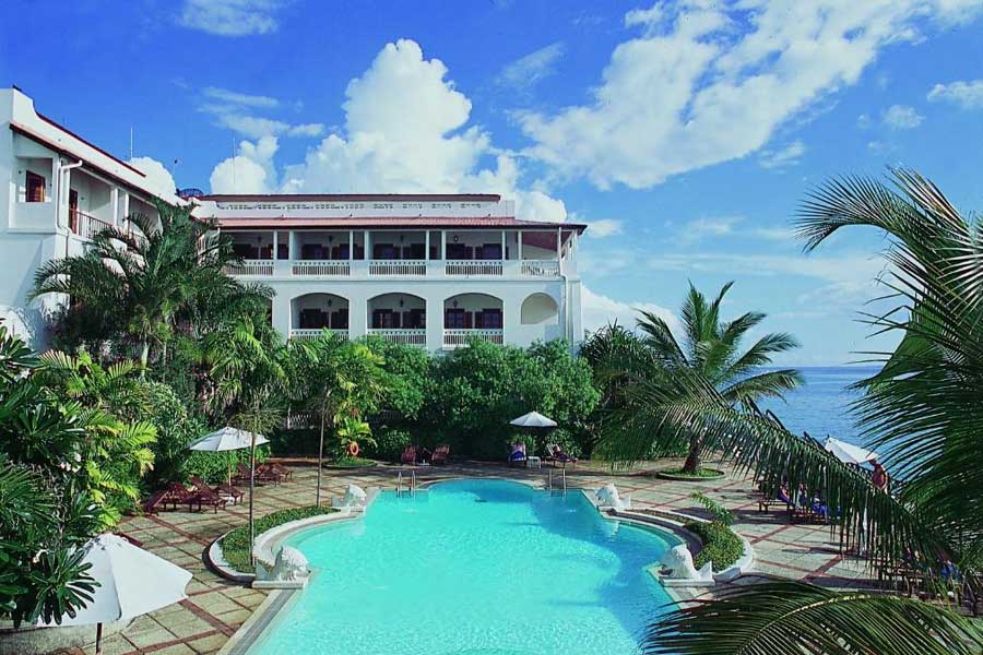 Luxury beachfront hotel swimming pool surrounded by palm trees and ocean views